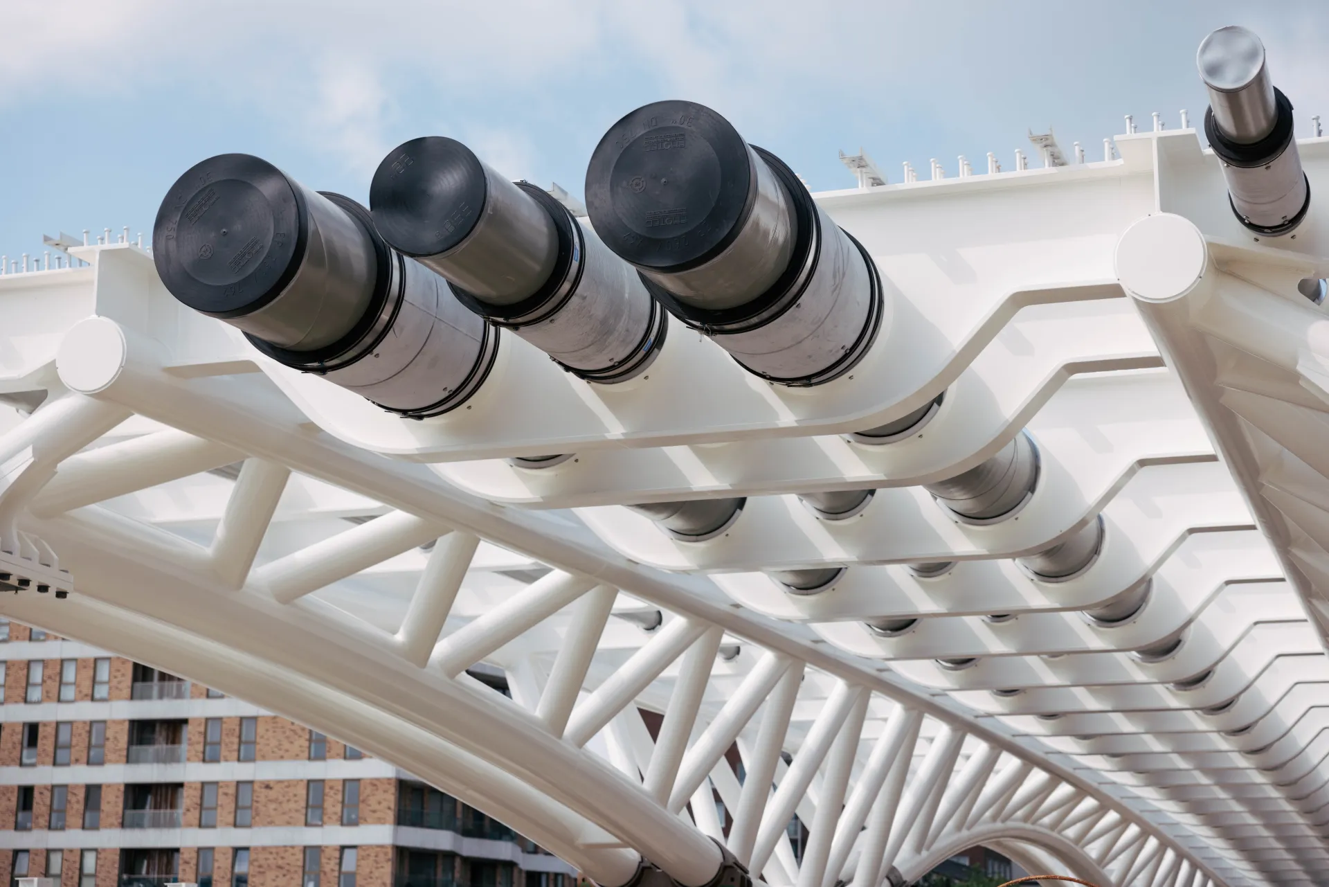 Witte stalen leidingbrug met gebundelde leidingen in stedelijk gebied