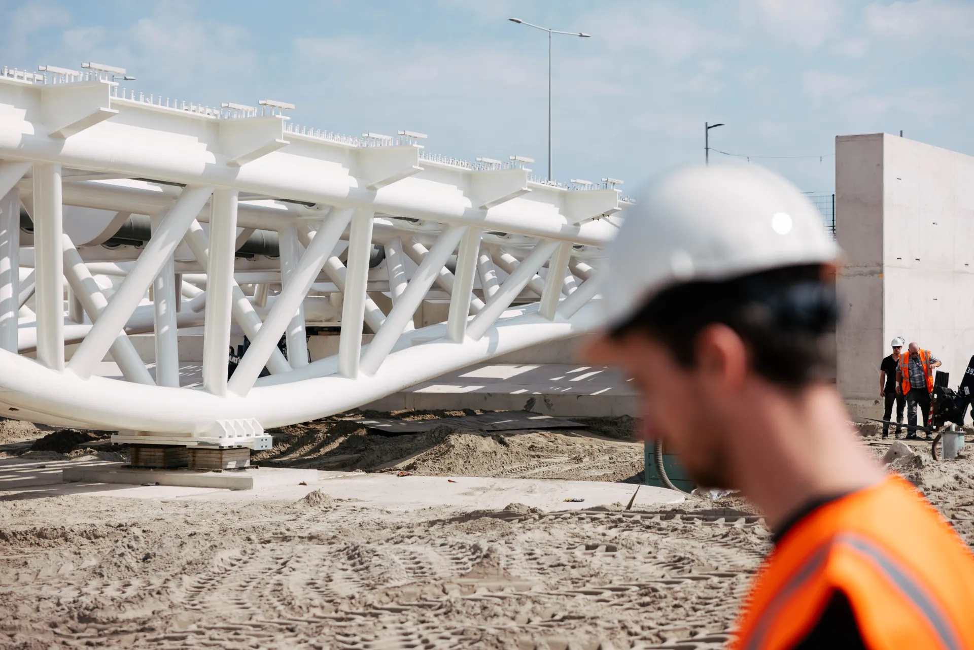 Toezichthouder met witte helm op een bouwterrein voor een witte vakwerkconstructie